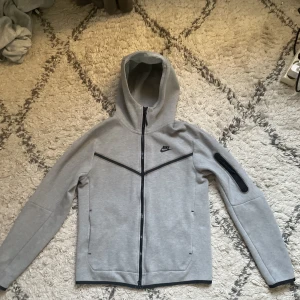 Nike tech kofta  - Nike tech kofta grå nästa ny har inte använt den så mycket se som ny ut men dock så har den man ska hänga den me har nästa gått sönder eller tråden på den men annars jätte fin och ny ingen fläck eller nått❤️