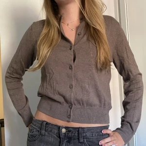 Kofta - Tunn kofta i en beige/brun färg. Köparen står för frakten. 