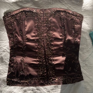 Glittrig korsett - En korsett med massvis av detaljer, perfekt för fest! Hör av er vid frågor