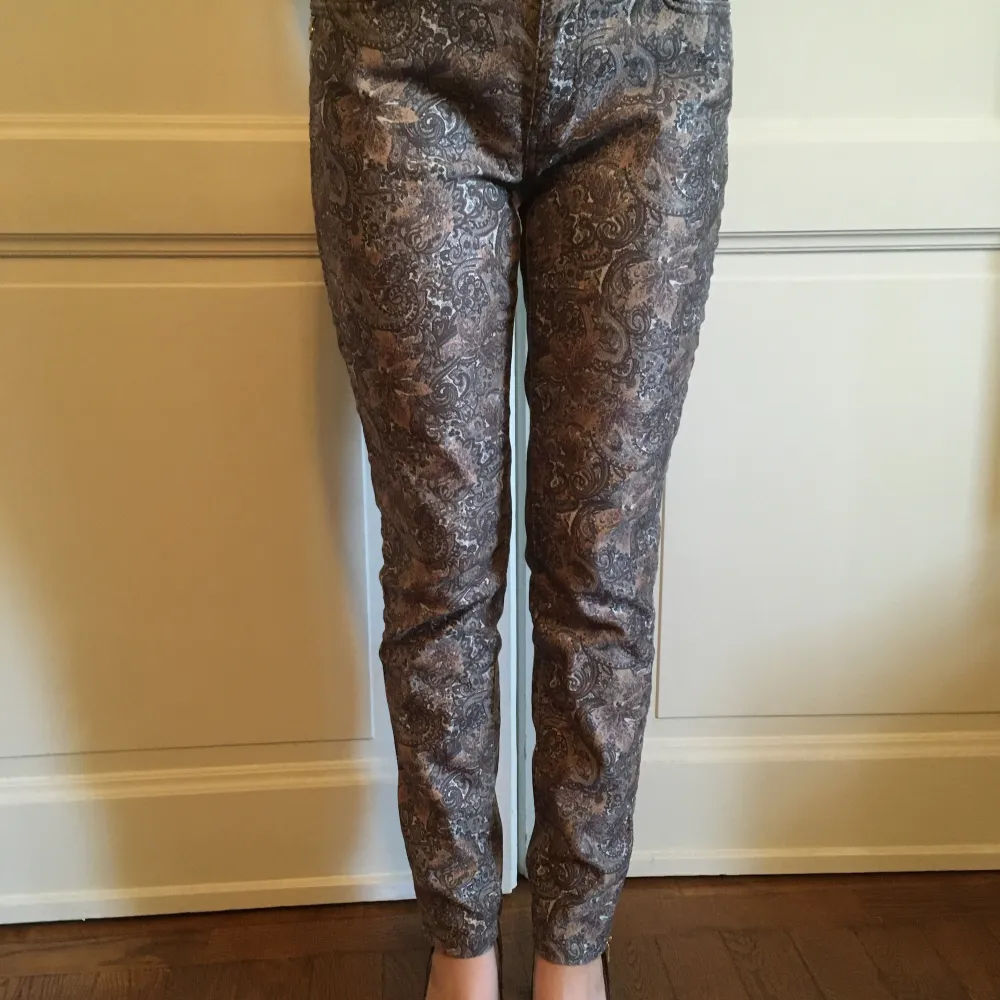 Mos Mosh Victoria Jive Pant - Metallic Choco Chip mönstrade byxor/jeans. Två framfickor, två bakfickor, dragkedja nere vid vristen, gulddetaljer. Midja är mellanväg.  Storlek: 27 Längd: 97 cm . Jeans & Byxor.