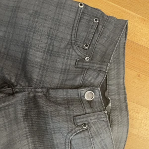 Jeans - Coola och unika svarta jeans med ett rutmönster. Även snygga ”kristall” liknande knappar.  Raka med lågmidja. 
