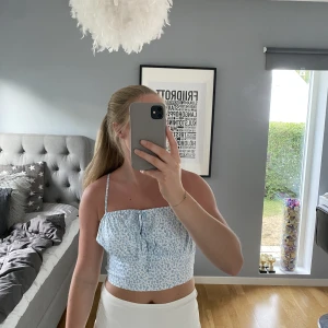 Blommigt linne - Säljer mitt blå vit blommiga söta linne från NA-KD i storlek 36 då det inte används längre. Liten knytning framtill och i väldigt bra skick. 