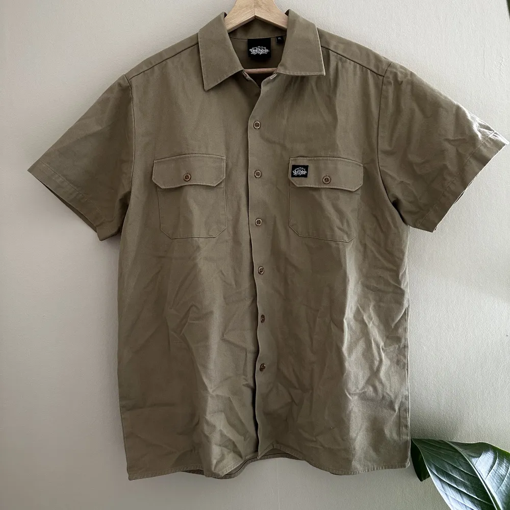 Skit snygg kortärmad overshirt eller tjock skjorta. Broderad detalj på ryggen. Storleken är XL men passar mindre beroende på hur man vill ha passformen. Perfekt plagg att bara ha över en simpel t-shirt för att lyfta sin outfit. Skjortor.