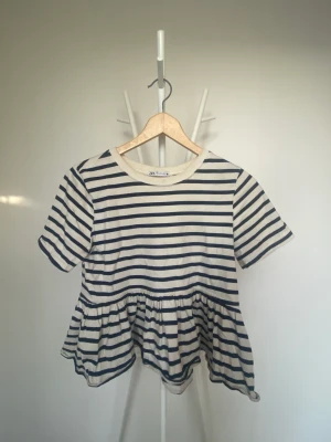 Zara t-shirt - En zara tröja med randigt mönster i vit och mörkblå med en stor volang längst ner på tröjan. Använd 1-2 ggr💕