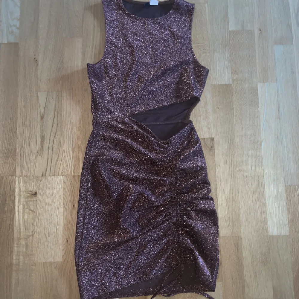 En brun glittrig klänning från H&M. Storlek XS. Säljer pga för liten för mig. Använd 2 gånger så den är i nyskick. Köparen står för frakt. Kan även mötas upp i Varberg.. Klänningar.
