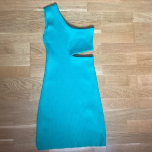 Grön ribbad klänning - Grön ribbad klänning från Pull&Bear. Klänningen är one shoulder och har en cut out under bysten på ena sidan. Mycket bra material och inte alls genomskinlig. Storlek S. Är aldrig använd. 