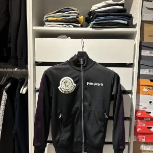 Palm angels x moncler  - En Palm angels x moncler hoodie i storlek small som e i väldigt fint skick. Den är i storlek small. Ny pris på denna ligger på 8000-9000 tusen kr. Jag har tyvärr inget kvitto. Jag kommer sälja denna för 6500 kr men priset kan diskuteras vid snabb affär.