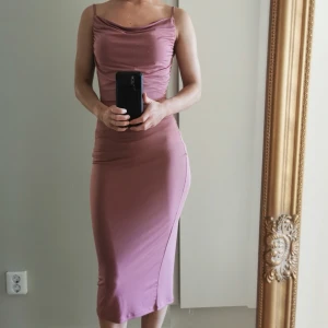 Rosa/lila klänning  - Figurnära midiklänning med draperad ringning. Fint skick.  Storlek XS
