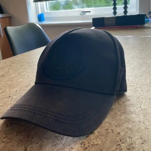 Moncler keps - Skick: 5/10, lite vita fläckar på sidorna-går troligtvis bort vid kemtvätt, lite brun längst fram, äkthetsbevis finns, skriv vid intresse!