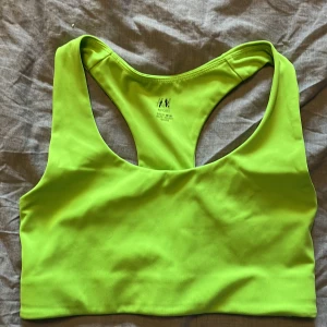 Sporttop - En grön sporttop/bh från hm. Säljer pga graviditet, kommer inte längre i plagget. Sitter skönt och har bra stöd för brösten. Ej kupor, men dubbla tyger. 
