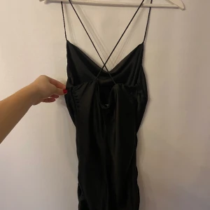 Silkesklänning - Svart silkesklänning med kors i ryggen och dragsko vid sidan. Märke: Zara. Storlek: S