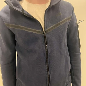 Nike tech hoodie  - Hej! Säljer min Nike tech hoodie i storlek M. Den är i bra skicka, använd under en halv sommar ungefär. Pris kan diskuteras.  POSTAR ENDAST!