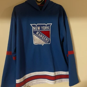 New York Rangers Jersey - Skitsnygg New York Rangers Jersey köpt från XXL. Märket är NHL International Shop och tröjan är NHL-licensierad, alltså inte replika. Den är lite liten på mig som har storlek M och men passar perfekt på min syster som har S även fast det står 164.