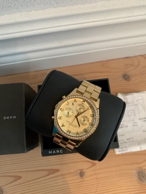 Guldig klocka Marc Jacobs - Guldig klocka med strass från Marc Jacobs, fint skick. Nypris 3 495kr, kvitto finns. Hämtas i Vasastan alternativt skickas.