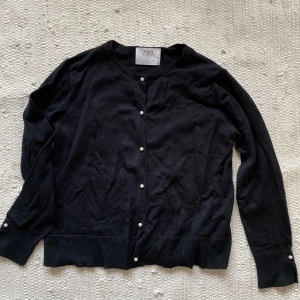 kofta med pärldetaljer - kofta som går att använda över som tröja. pärlor som knappar och en på vardera ärm. stlk 152 (barn) men skulle passa xxs-xs