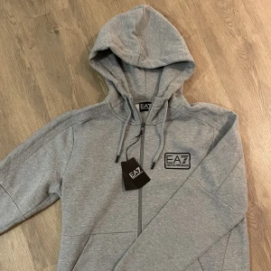 Emporio Armani EA7 Zip Hoodie storlek L - Nya och oanvända med etikett. Finns i L och XL. Finns att hämta i Täby men kan även skickas mot fraktkostnad.