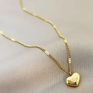 Ett guld smickrande halsband format som ett hjärta med en text lydande Love 🧡