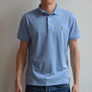 Ralph Lauren pike - Ljusblå ralph Lauren pike i skönt t shirt material och custom slim fit passform. Tröjan är i bra skick men har ett litet slitage vid nacken inuti tröjan. **EGNA BILDER EJ FRÅN HEMSIDA**