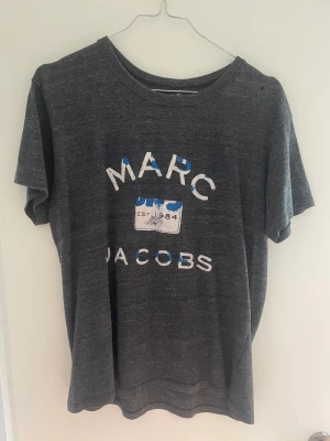 Marc Jacobs t-shirt - Marc Jacobs t-shirt i grått. Litet hål på sidan som är lätt att sy ihop, därav lågt pris!! 