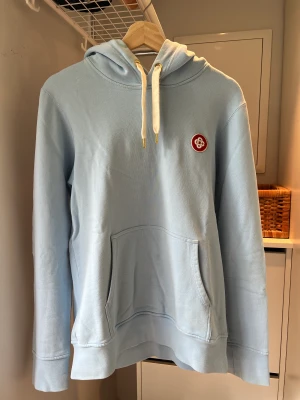 Casablanca Hoodie pastellblå - Sjukt snygg hoodie från Casablanca med gulddetaljer och märkets ikoniska logga broderad på framsidan. Mycket bra skick. Skön passform som är rymlig men inte för stor. 100% eko-bomull, hela plagget andas kvalitet. Kan skickas eller hämtas i Stockholm.