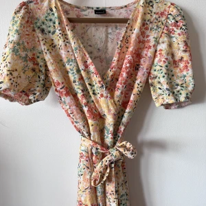 Blommig kort klänning - Blommig kort klänning med band i midjan! (Avtagbart)! Puffärmar. Mjuk klänning i bomull! Supersöt till sommaren eller över jeans för en coolare höst-look :) 