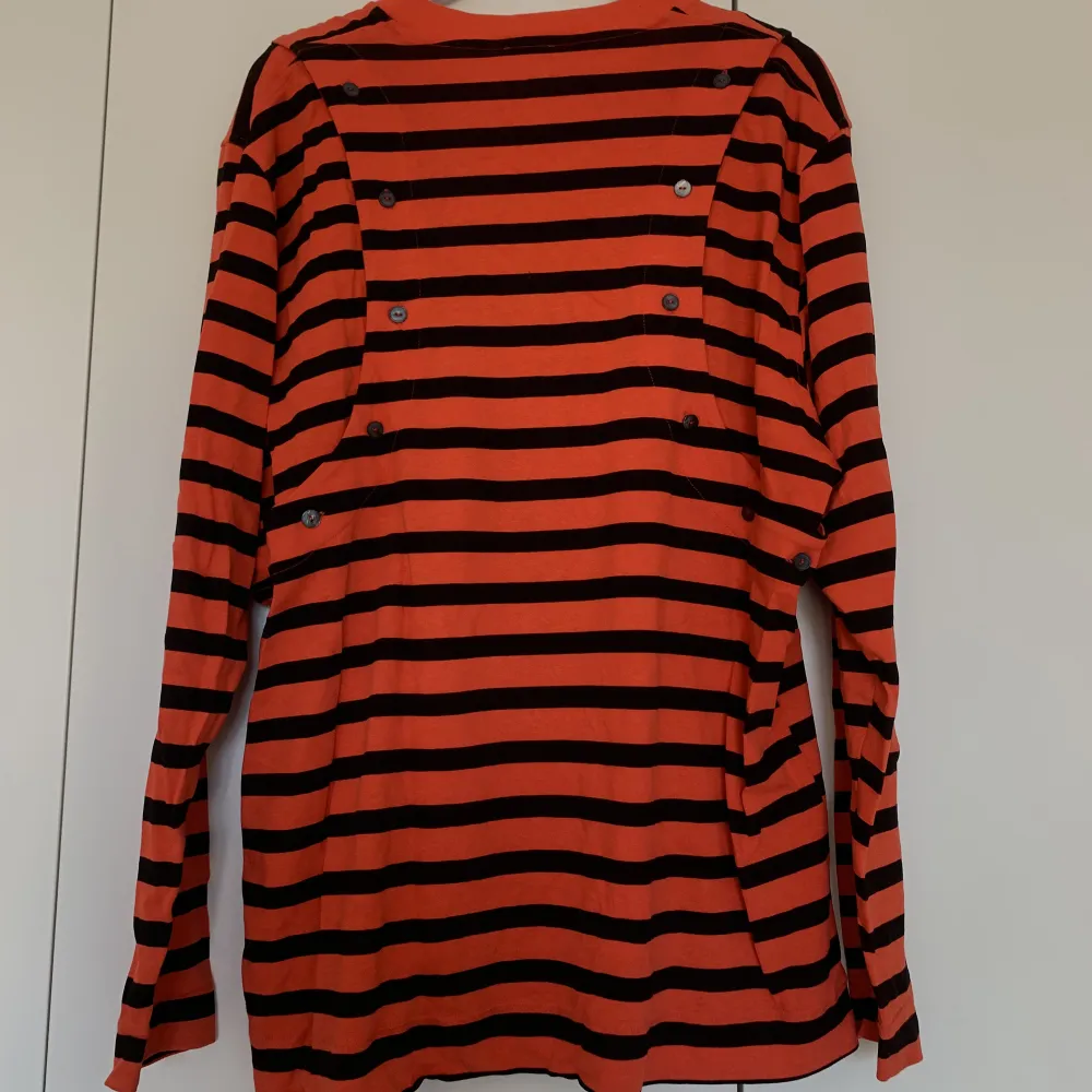 Never been used orange and black striped H&M studios T-Shirt in a thicker cotton quality. Oversized and removable sleeves with buttons on each arm. . Tröjor & Koftor.