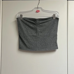 Dark grey melange tubetop - Mörkgrå stretchig tubetop från HM 🩶 På insidan finns ett extra lager vid bysten för extra comfort och support ☺️Stretchigt och mysigt material ☁️ Bra att layer med andra plagg till höst 🍁Utmärkt skick, endast använd fåtal gånger! 