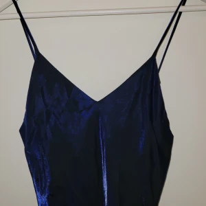 Mörkblå aftonklänning  - Mörkblå skimrande långklänning. Går ner till golvet på mig som är 160 cm. Tyget är lite nött på ett ställe, syns på sista bilden. 