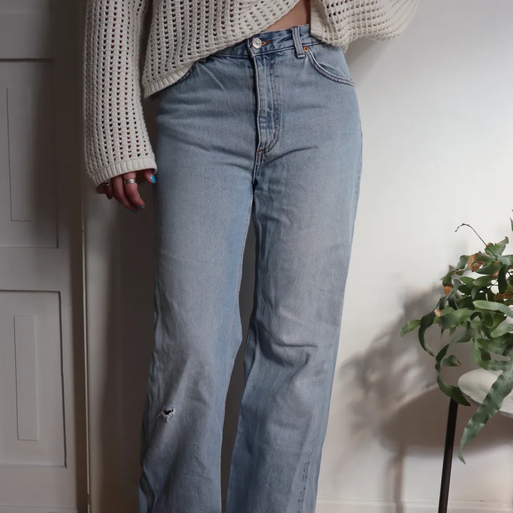 Ljusblåa jeans från Monki. Högmidjade och vida i benen (modellen är 172cm). Har ett snyggt hål som detalj på ena benet. Bra skick! Säljer för jag ej kan ha dom längre 🫧. Jeans & Byxor.