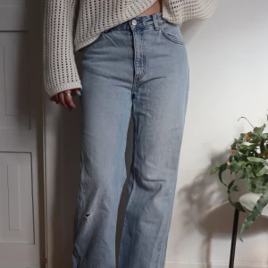 Vida blåa monki jeans - Ljusblåa jeans från Monki. Högmidjade och vida i benen (modellen är 172cm). Har ett snyggt hål som detalj på ena benet. Bra skick! Säljer för jag ej kan ha dom längre 🫧