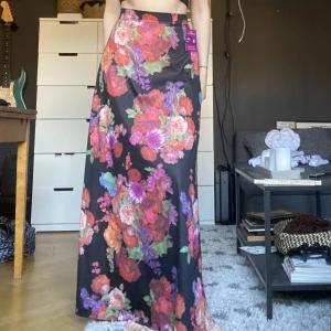 Långkjol - Säljer denna vackra maxikjol med blommor. Har innerkjol. Köpt vintage för 450kr men säljer för 250. Högmidjad. Stängs med dragkedja + en knapp i ryggen. Jättefint skick. Mått: midja: 68cm. Längd: 107cm ❤️