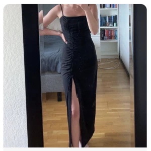 Långklänning med slits - Lång klänning med slits , reglerbara axelband, öppen rygg med knäppning och dragkedja bak. Använd 1gång.