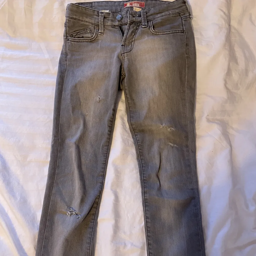 snygga låga gråa jeans som sitter bra🩶dem är avklippta där nere och därför lite korta för mig som är 166 så dessa passar nog någon som är kortare än mig🥰 dem har en splitt där nere och är i en fin grå färg!. Jeans & Byxor.