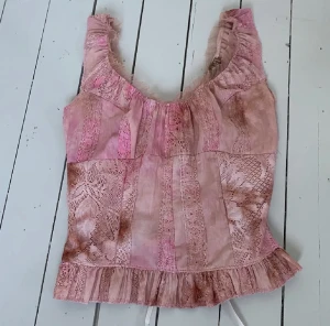 Show girls topp - Söt rosa topp men snörning i ryggen så att man kan justera hur tajt man vill att den ska sitta! Show girl topp!  I bra skick! Har ingen storlek så skulle säga att den passar som xs-M eftersom man kan justera den!