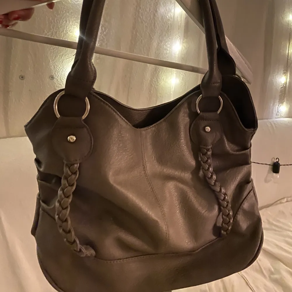 En brun/grå skinn väska med två flätor på framsidan. Mellan stor väska och passar nästan till allting 💕. Väskor.