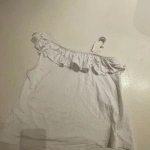 One shoulder volangtopp - Säljer denna assnygga one shoulder volangtopp från gina tricot young! Säljer på grund av att den inte riktigt kommer till användning lika mycket. Toppen har en liten fläck längst ner till vänster på baksidan, syns inte, går nog att ta bort. Nypris 150 kr