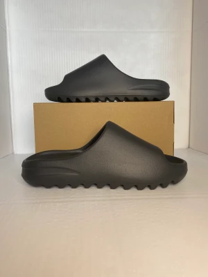 Yeezy slides, onyx - Strl: EU 43 US 9 Helt nya Yeezy slides Onyx från adidas CONFIRMED.  Cond:10/10 Digitalt kvitto ✅ Box✅ Köparen står för frakten 🚚  Bara skriv om du har några frågor eller funderingar. 