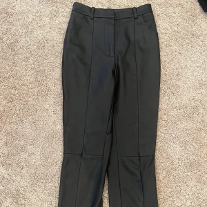 Läderbyxor  - Byxor i läderimitation från NA-KD i flare modell. Storlek 34/36, fint skick!