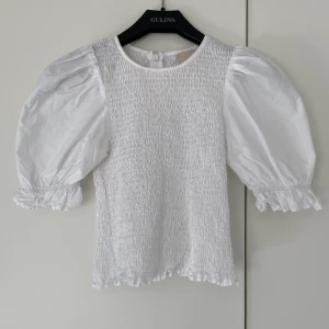 Vit blus med puffärmar - En söt vit  blus från H&M med puffärmar och smock. Liten sminkfläck vid högra axeln, syns knappt men går att få bort med typ Vanish!