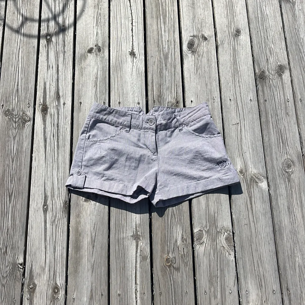 Blå randiga lågmidjade sommarshorts med broderi POXY på framsidan och ”Remember your Roots” på baksidan. Shortsen är justerbara i midjan. Säljer då de är en aning för små för mig.. Shorts.