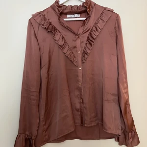 Elegant blus/skjorta - Elegant blus/skjorta i satin. Tyget är fint och tunt i en rostrosa färg. Använd men i väldigt fint skick.