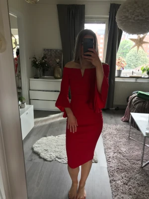 Klänning - Röd tight klänning med slits baktill, mjukt material och vida armar nedtill. Använd en gång.