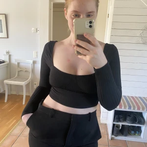 Kort långärmad topp - Svart topp med fin urringning. Storlek 38.