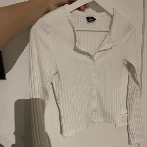 En vit långärmad tröja med knappar - En vit långärmad tröja med knappar från Gina. Den är i storlek xs. Säljer den för 50kr plus frakt. 
