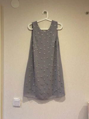 Klänning  - Säljer min gråa blomm klänning då den inte kommer till användning, helt som ny. Ny pris 750kr säljer för 150kr skriv för fler frågor osv. 