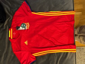 Fotbollströja  - T-shirt från adidas med tryck. Som ny, aldrig använd då lapp sitter kvar. Kan mötas upp annars står köparen för frakt! 
