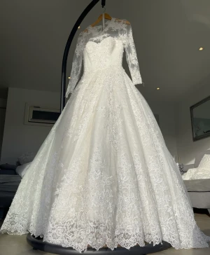 Brudklänning bröllopsklänning med ärmar + brudslöja. KEMTVÄTTAD - Köpt hos proms and wedding ca 40 000kr. Sytt till armar hos proms and weddings. Kemtvättad redo att användas. Underkjol finns och följs med för en extra effekt.7 lager tyg Storlek är justerbar med snörning i rygg. Nyskick