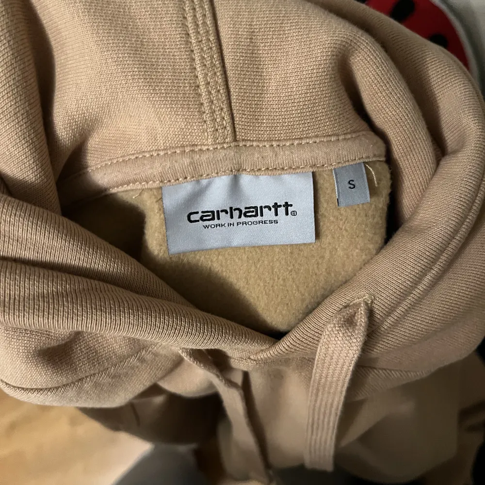 Beige/brun Carhartt hoodie mjuk och skön i nytt skick. Tjock Baggy hoodie som passar perfekt på mig som är brukar bära S-M. Passar perfekt för hösten/vintern. . Hoodies.