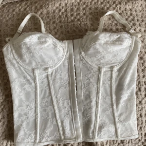 Korsettopp i spets  - Vit korsettopp i spets. Väldigt fin i ryggen. Endast använd 1 gång så som ny.