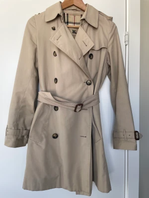 Burberry trenchcoat  - Klassisk trenchcoat från Burberry, 2 trasiga knappar, lätt att byta. Använd, men i fint skick